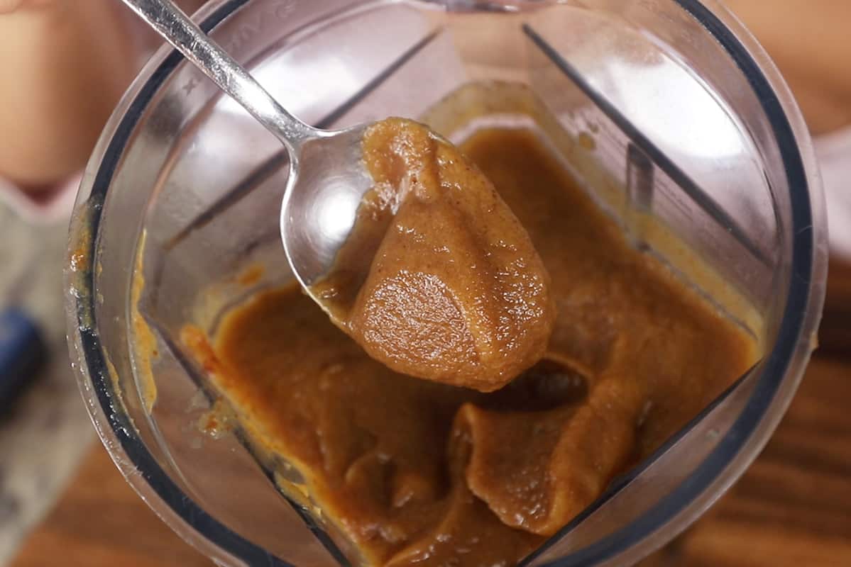 scooping date caramel out of a blender