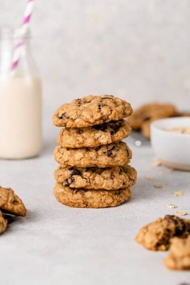 vegan oatmeal raisin cookies in a tall stack with a glass of oat milk by sweet simple vegan