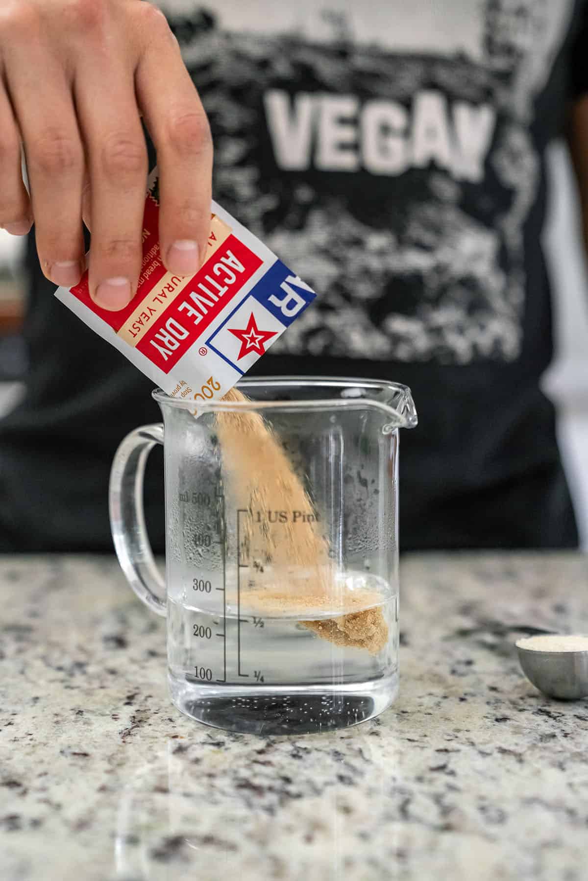 pouring active dry yeast into a glass with hot water