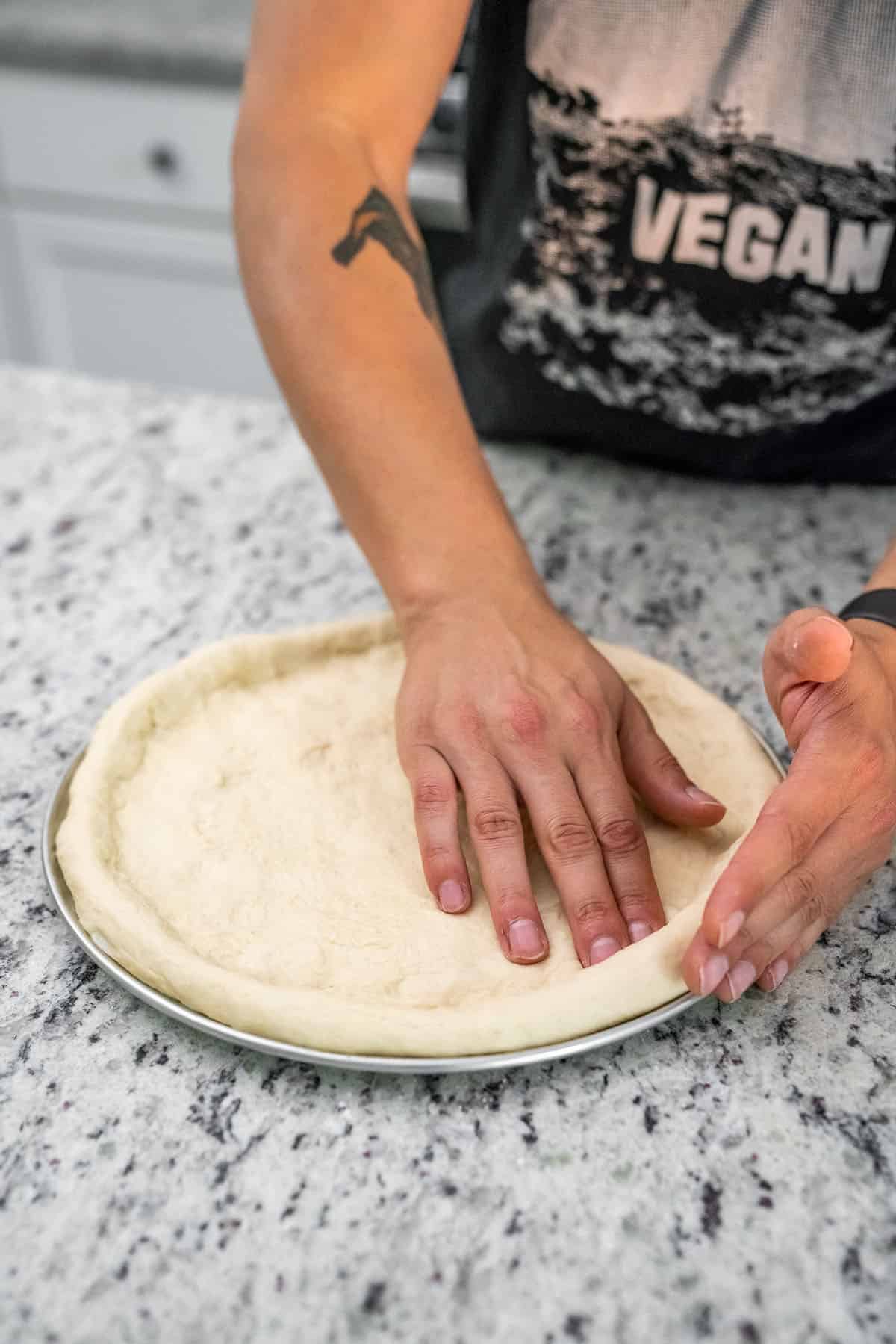 putting pizza dough on prepared pan