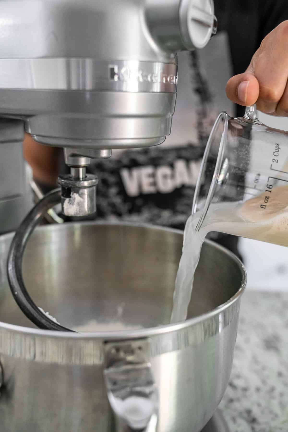 pouring activated yeast into stainless steel standing mixer