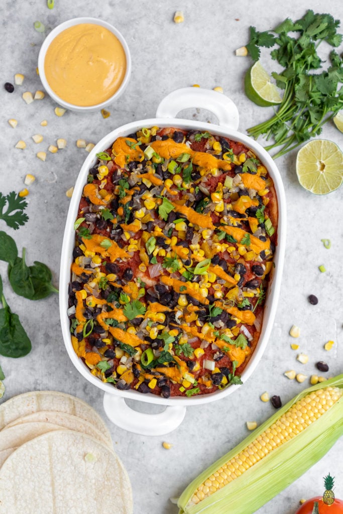overhead image of vegan enchilada casserole styled on grey background. 