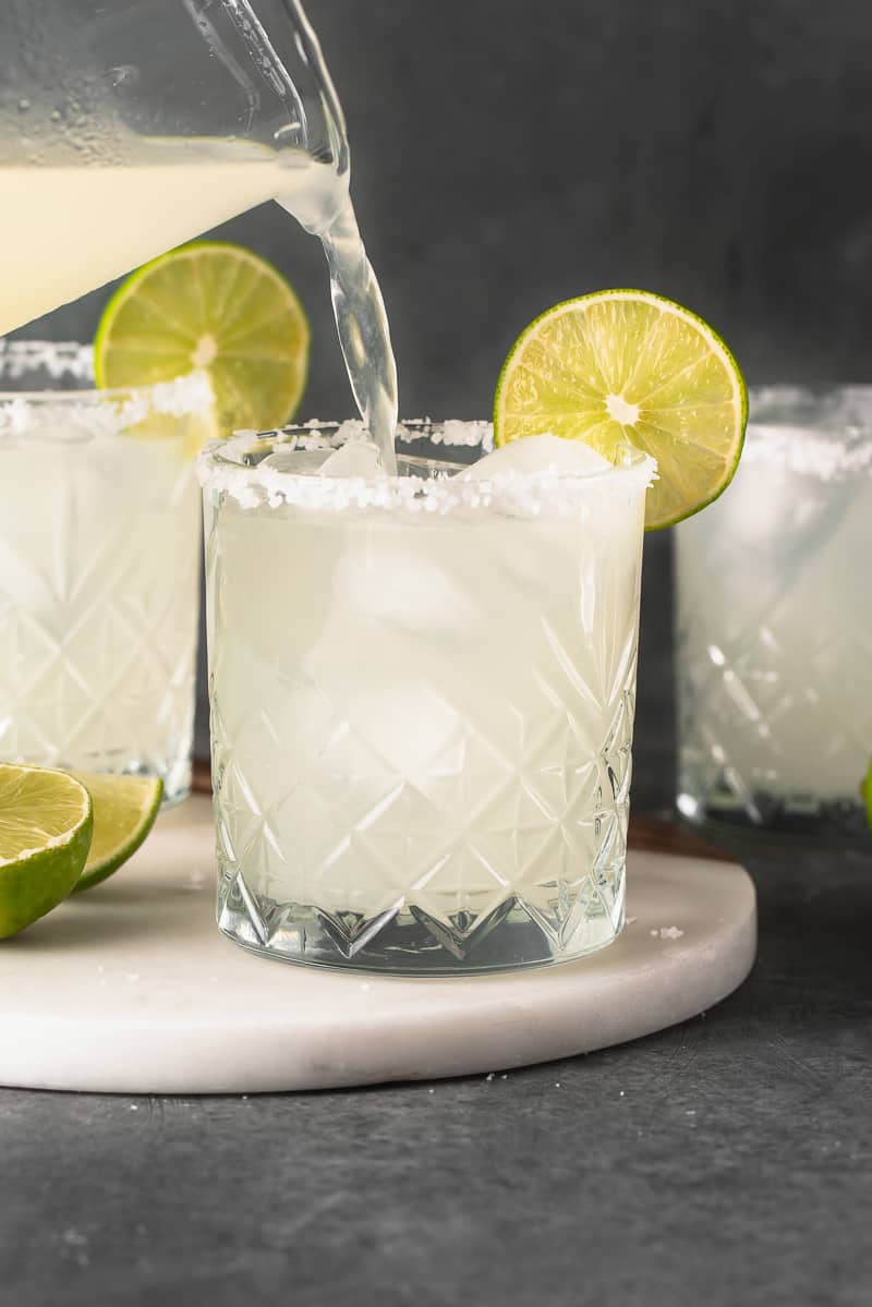 classic margarita being poured into a glass from the pitcher