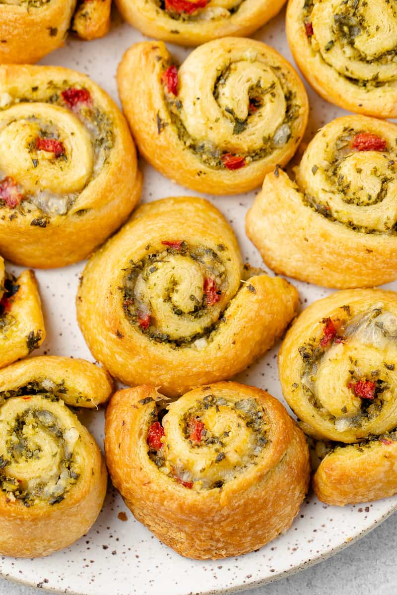 close up photo of vegan pesto pinwheels on a white speckled plate