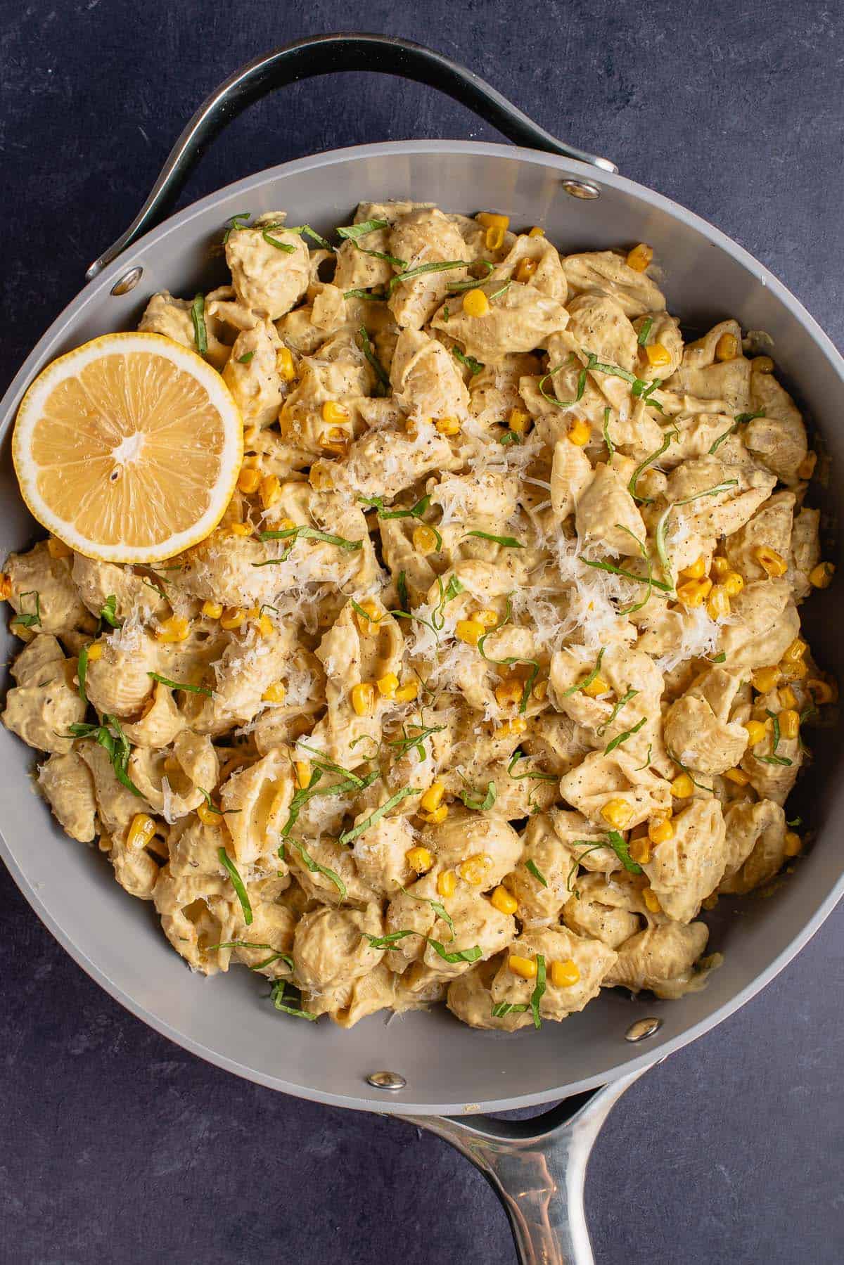 pan filled with creamy corn pasta and a lemon