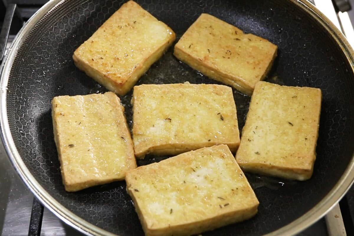 breaded tofu frying in cast iron skillet