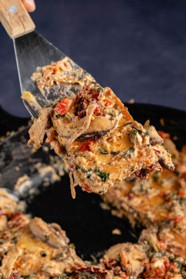 spatula with Creamy Tuscan Vegan Chicken in cast iron skillet