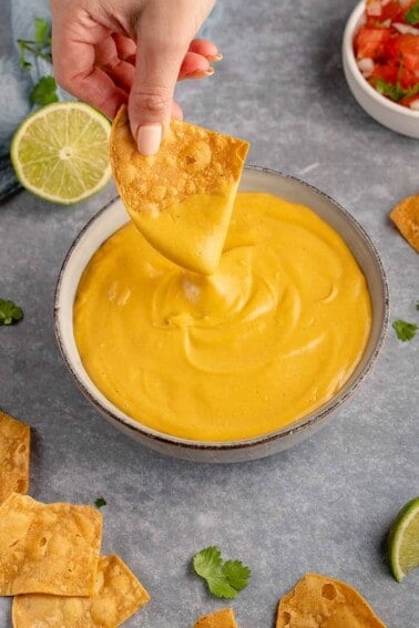 dipping tortilla chip into vegan nacho cheese