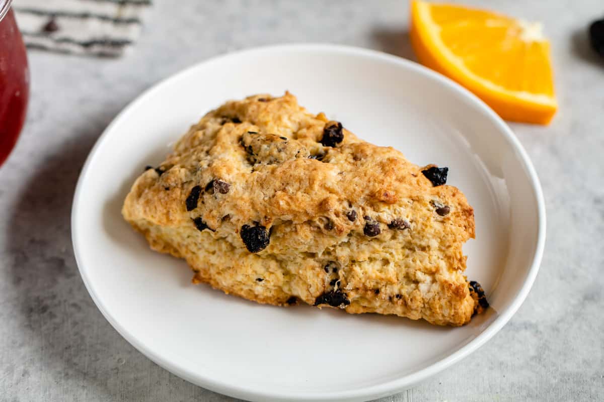 horizontal photo of dried chocolate cherry scone on white plate