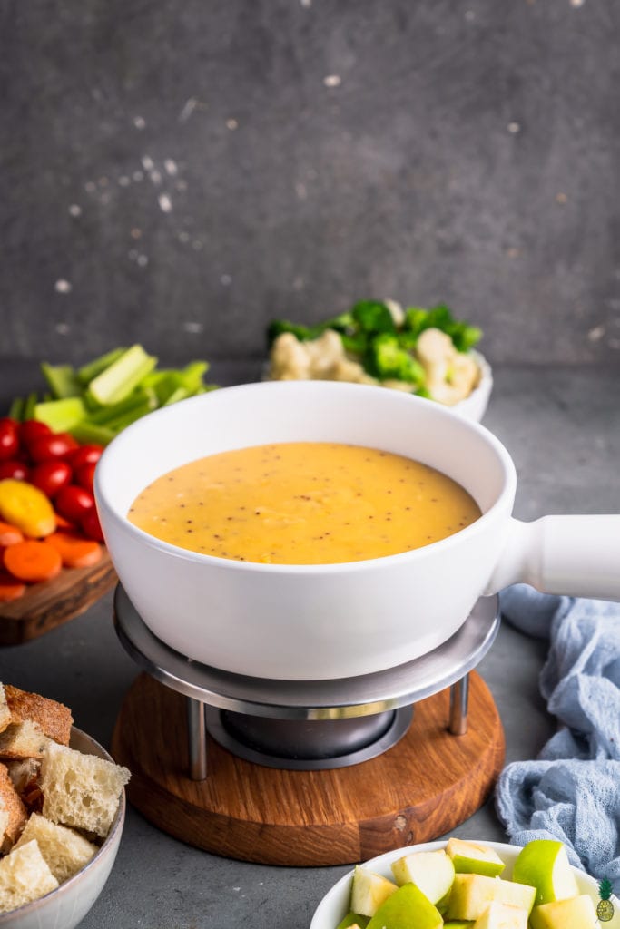 vegan cheese fondue in a white pot surrounded by dippers by sweet simple vegan