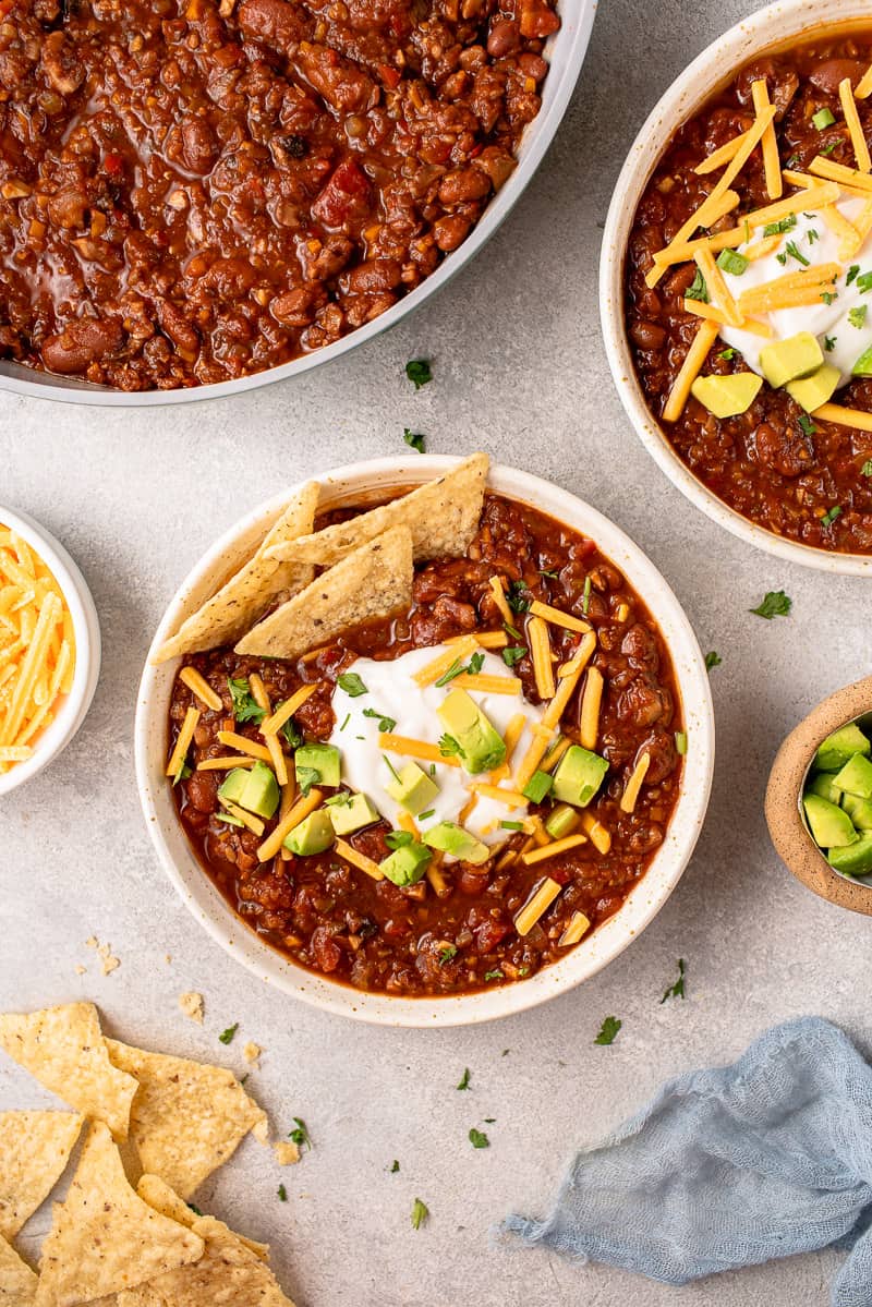 overhead image of bowls of chili styled with vegan cheese and chips