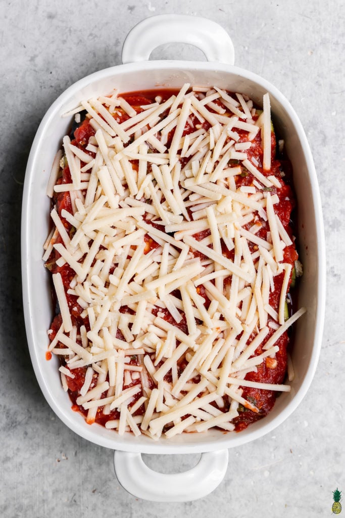 overhead image of eggplant rollatini in a baking dish with cheese and sauce uncooked