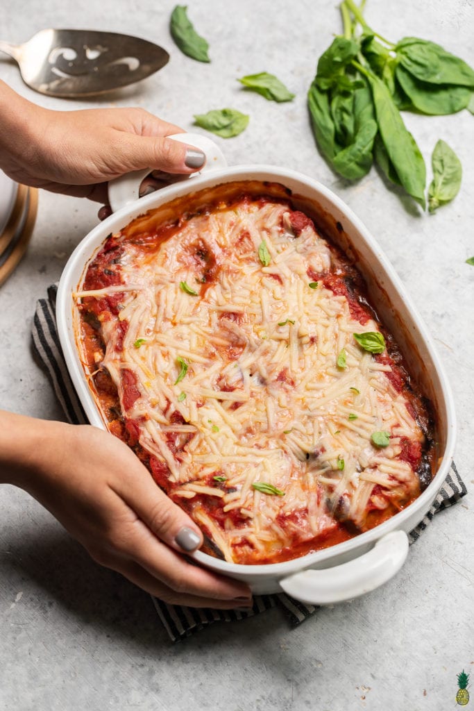 Christmas Recipe - overhead image of eggplant rollatini in baking dish being placed onto table