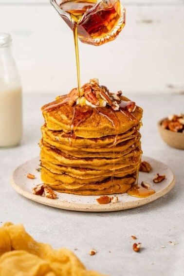 up close image of syrup being poured onto pumpkin pancakes