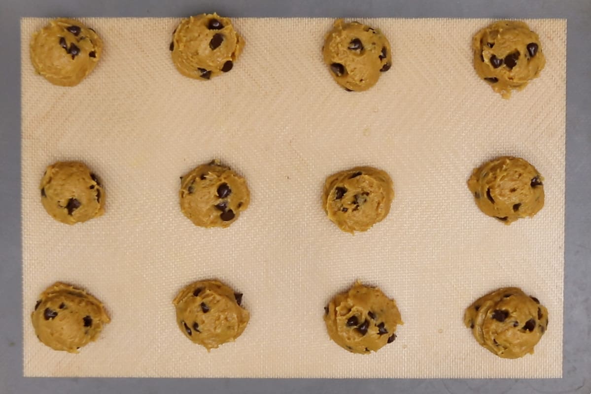 pumpkin chocolate chip cookie dough on lined baking sheet before baking