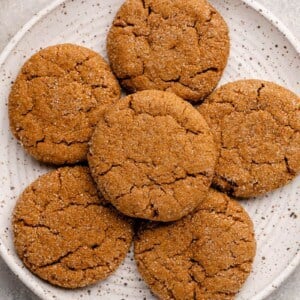 overhead shot of vegan ginger molasses cookies on a white speckled plate with a blue towel