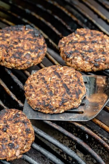 a spatula with a charred veggie burger on a grill