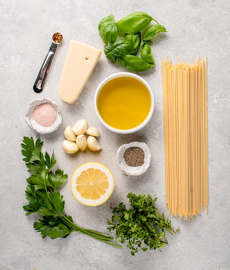 ingredients to make garlic and herb pasta on a gray board