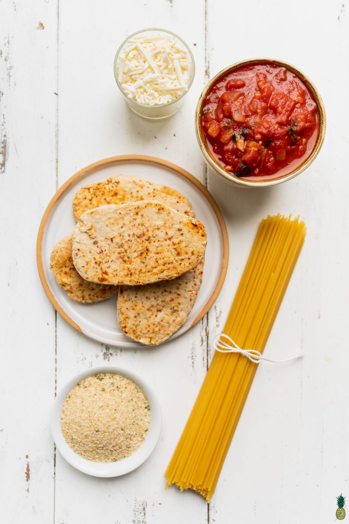 Ingredients to make vegan chicken parmesan on a wooden board by sweet simple vegan blog