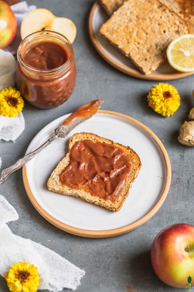 a jar of apple butter and a butter knife with a piece of toast with apple butter by sweet simple vegan