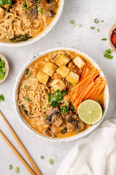 a white bowl of one pot red curry ramen on a gray board by sweetsimplevegan
