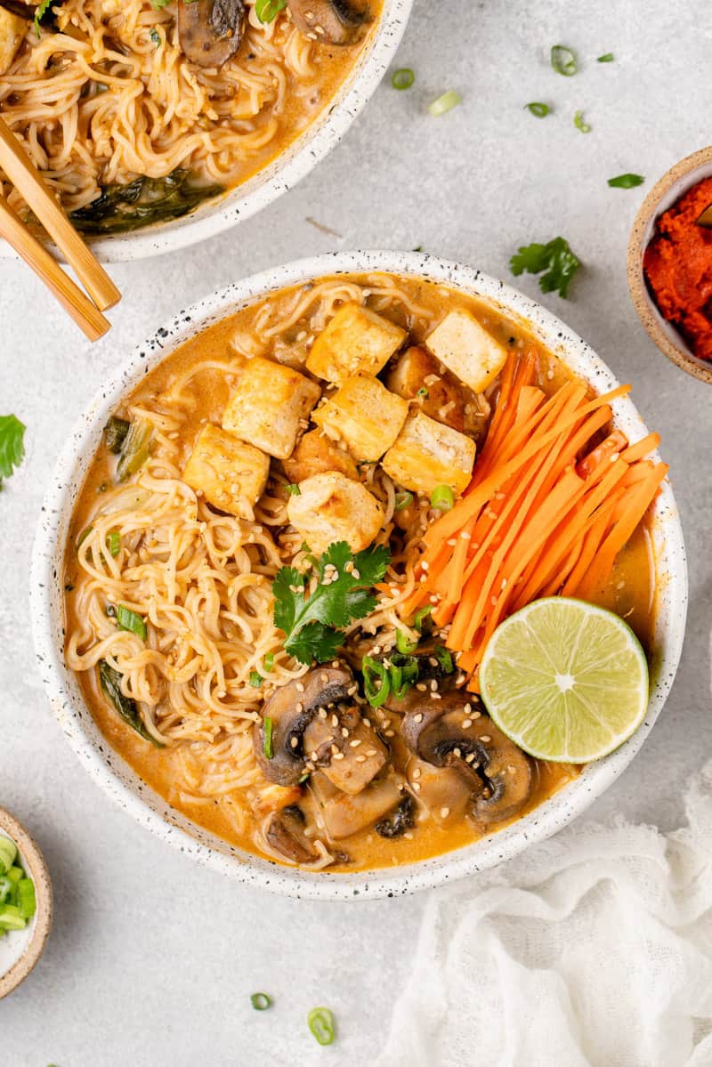 a white bowl of one pot red curry noodle soup on a gray board by sweetsimplevegan