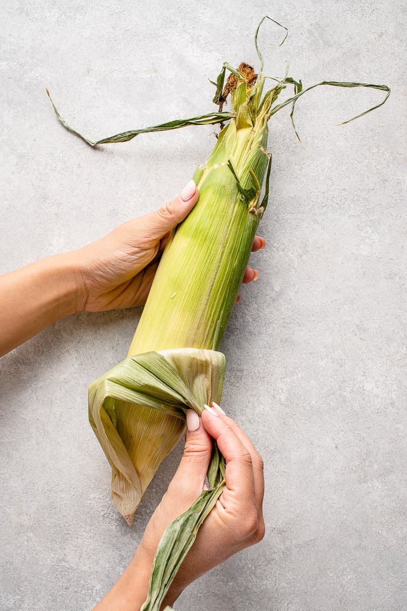 peeling husk off of corn