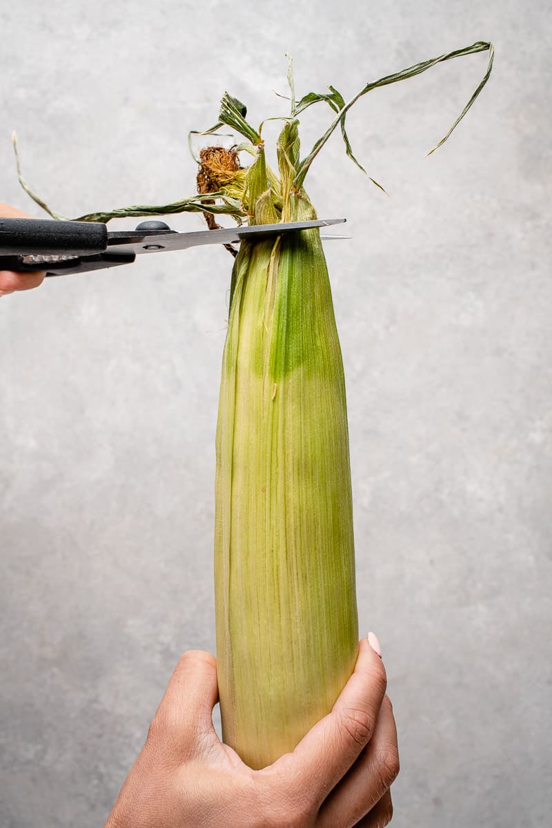 photo of scissors trimming the husk on corn