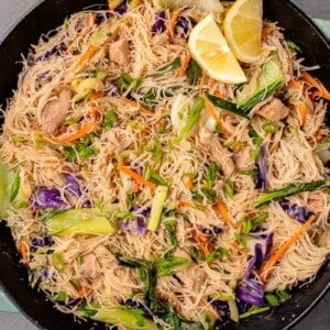 overhead image of vegan filipino pancit bihon with chicken in a wok with lemon