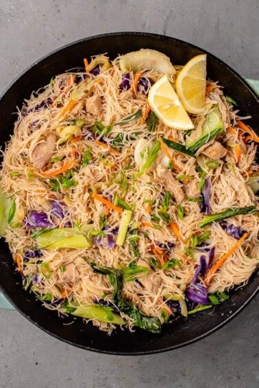 overhead image of vegan filipino pancit bihon with chicken in a wok with lemon
