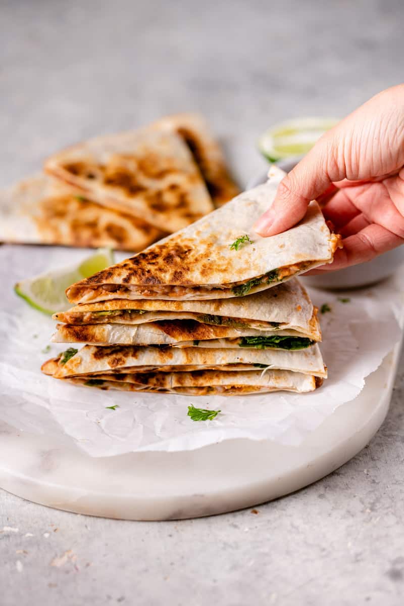 stacked slices of potato and bean quesadillas with one being picked up