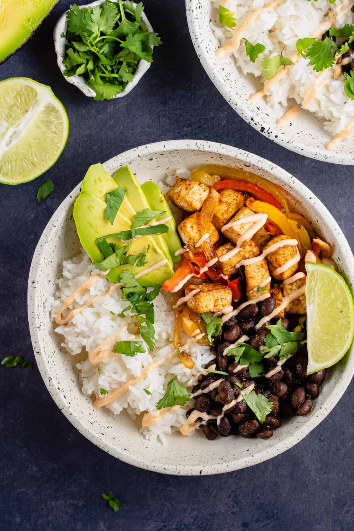 white bowl of tofu fajitas with black beans, lime and chipotle cream