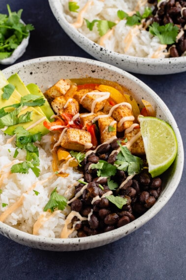 white bowl of tofu fajitas with black beans, lime and chipotle cream