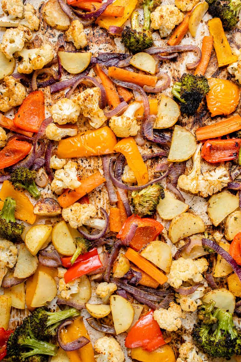 a close up of roasted vegetables on a silver baking sheet with a blue towel