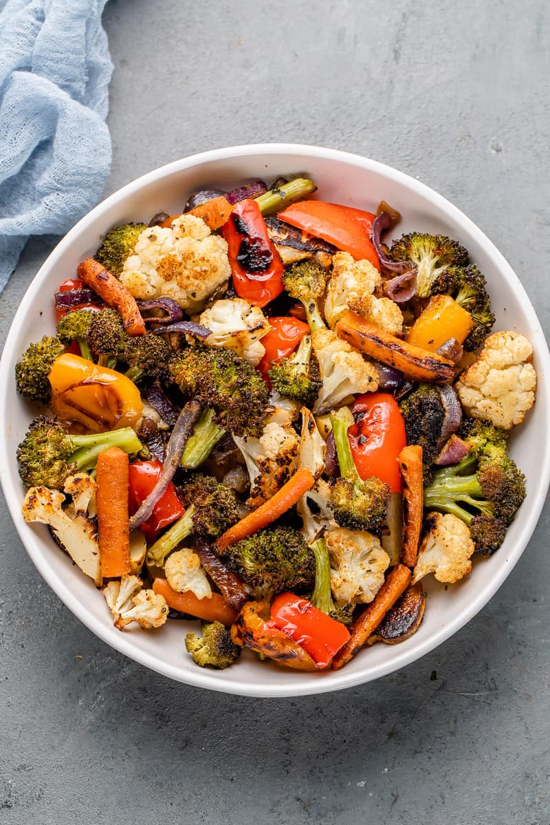 roasted vegetables in a white bowl with a blue towel