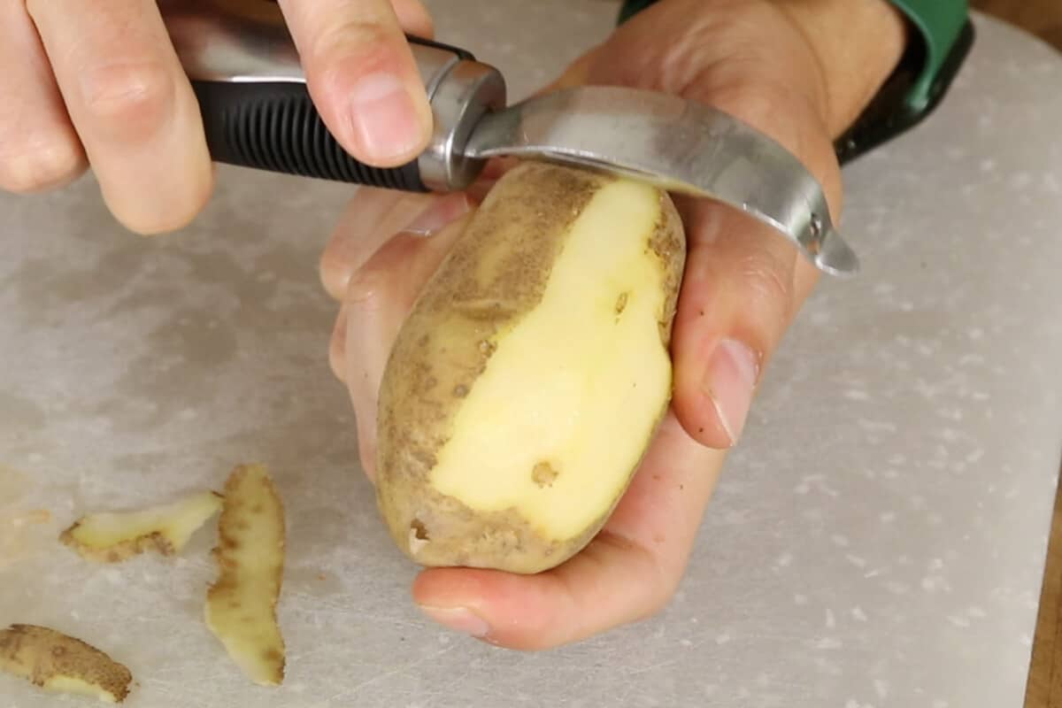 peeling russet potato with metal peeler