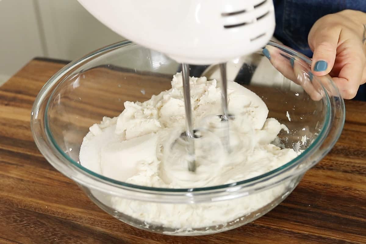 preparing nut-free vegan cheesecake filling in a glass bowl with hand mixer