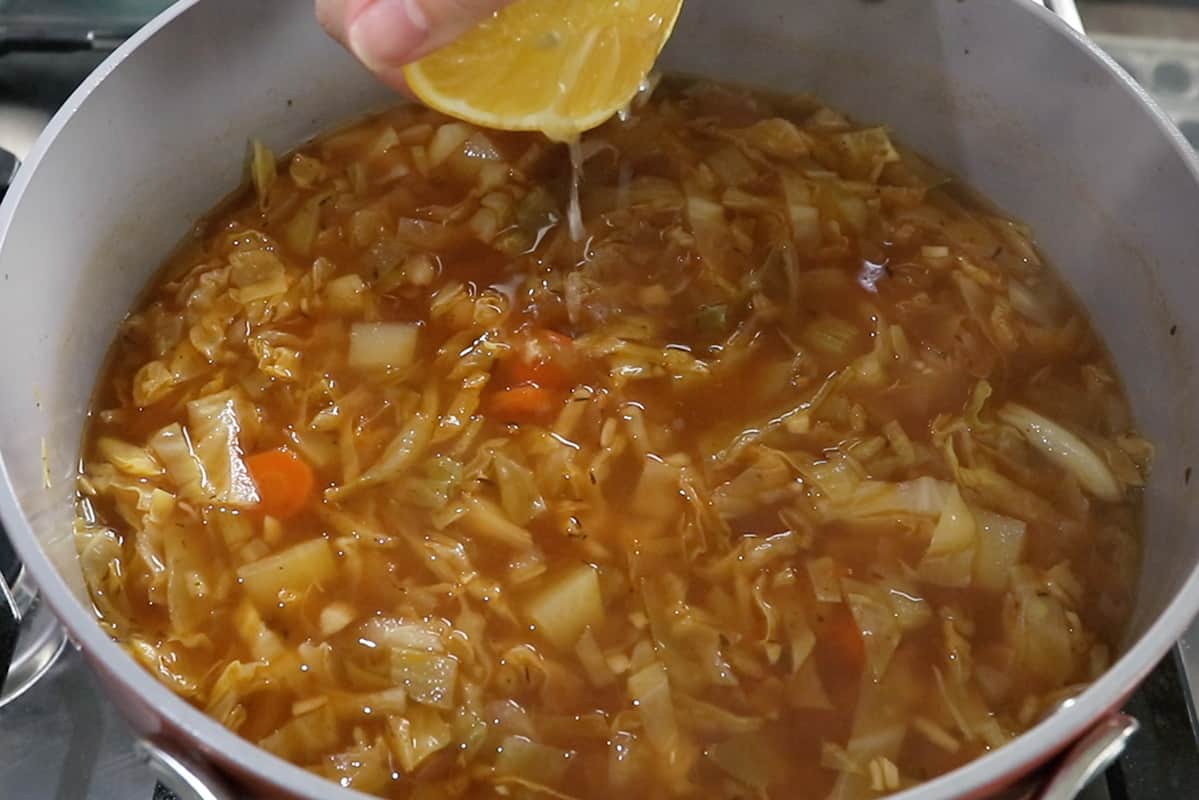 adding fresh lemon juice to cabbage soup in large pot