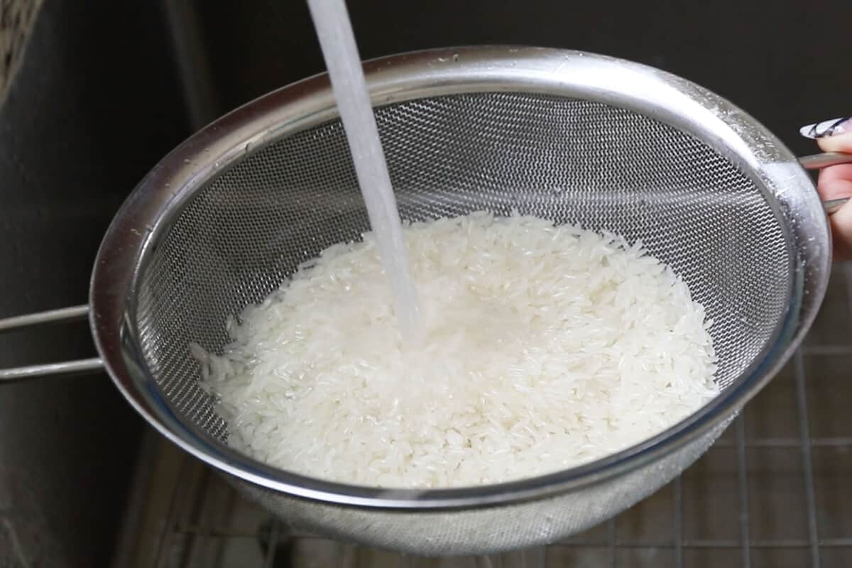 step by step - white rice being rinsed in a strainer