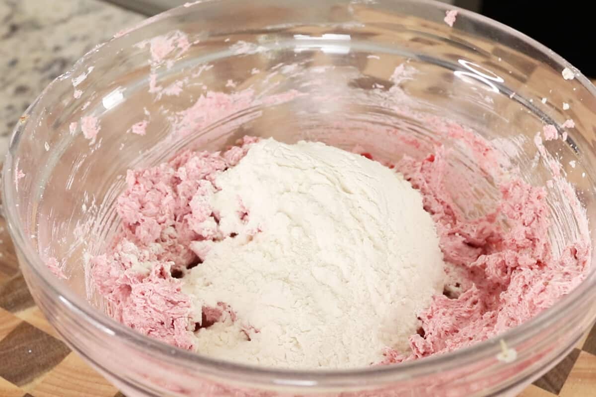 making strawberry cookie dough with hand mixer in glass bowl