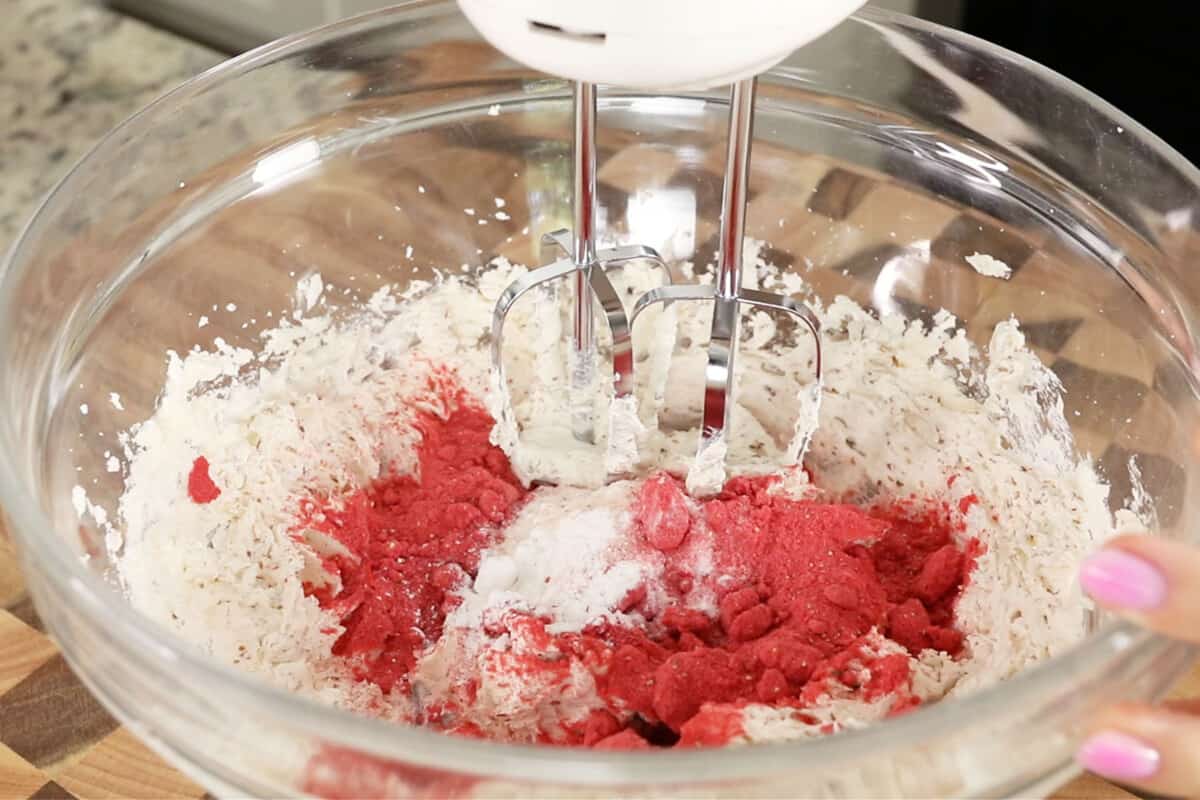 making strawberry cookie dough with hand mixer in glass bowl