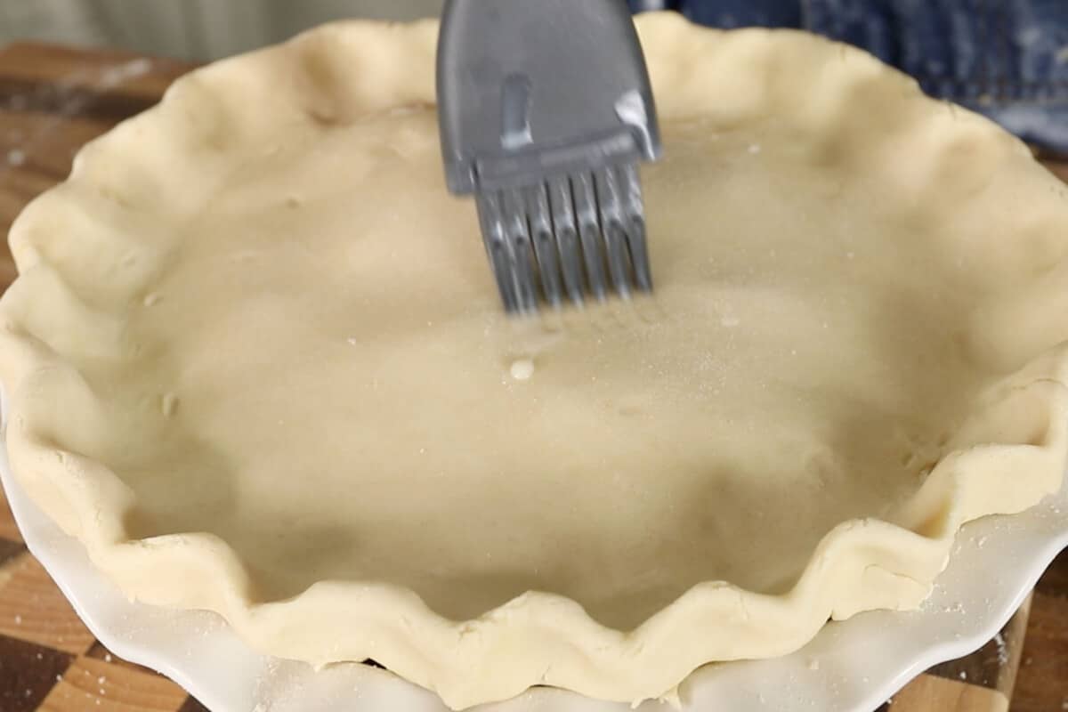 brushing vegan apple pie with almond milk before baking