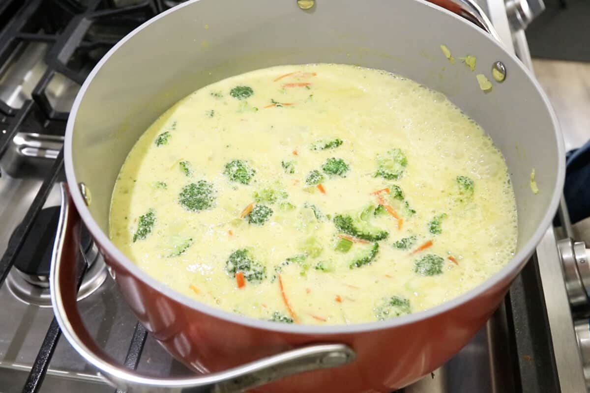 making vegan broccoli potato soup in large pink pot
