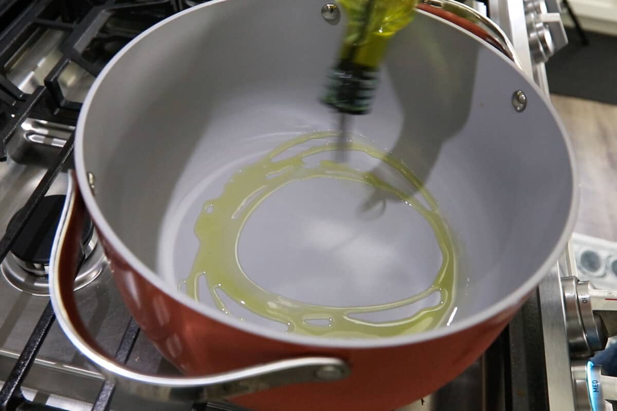 hand drizzling oil into large pot