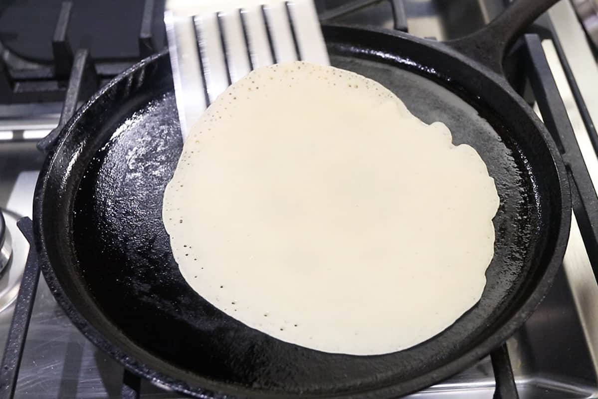 using metal spatula to flip crepe on cast iron griddle