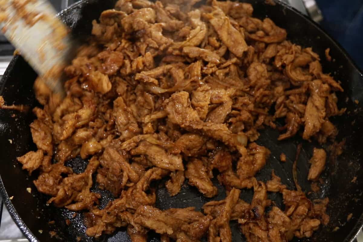 cooking soy curls for vegan cheesesteak in cast iron skillet