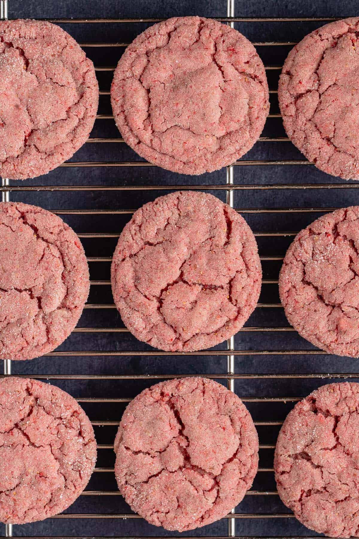 vertical photo of 9 strawberry sugar cookies on a silver cooling rack