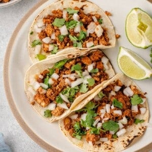 vegan tofu tacos on a white plate with onions and cilantro
