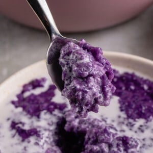 close up photo of spoon scooping ube champorado from white bowl
