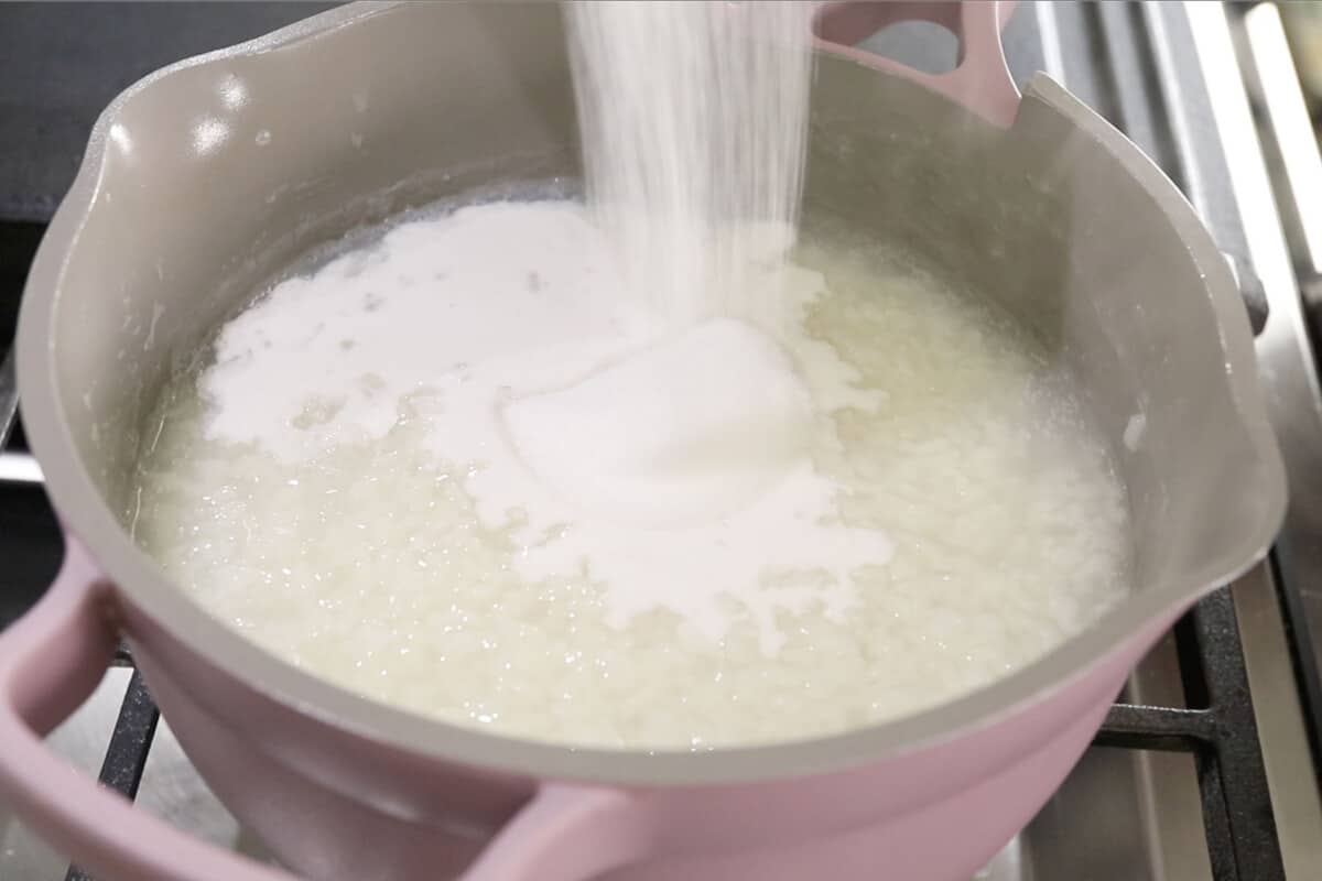 pouring sugar into rice for ube champorado